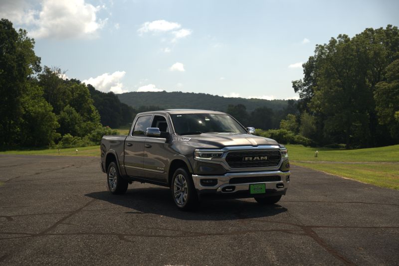Modern RAM 1500 crew cab pickup truck featuring chrome front grille parked outdoors on a paved road in a scenic rural environment.